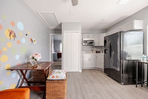 Una cocina moderna con armarios blancos, un refrigerador de acero inoxidable y un microondas.