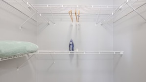 A minimalist room with white walls, a single white shelf, and a small blue object on the shelf.