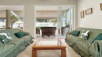 A living room with two green sofas, a wooden coffee table, and a wicker chair.