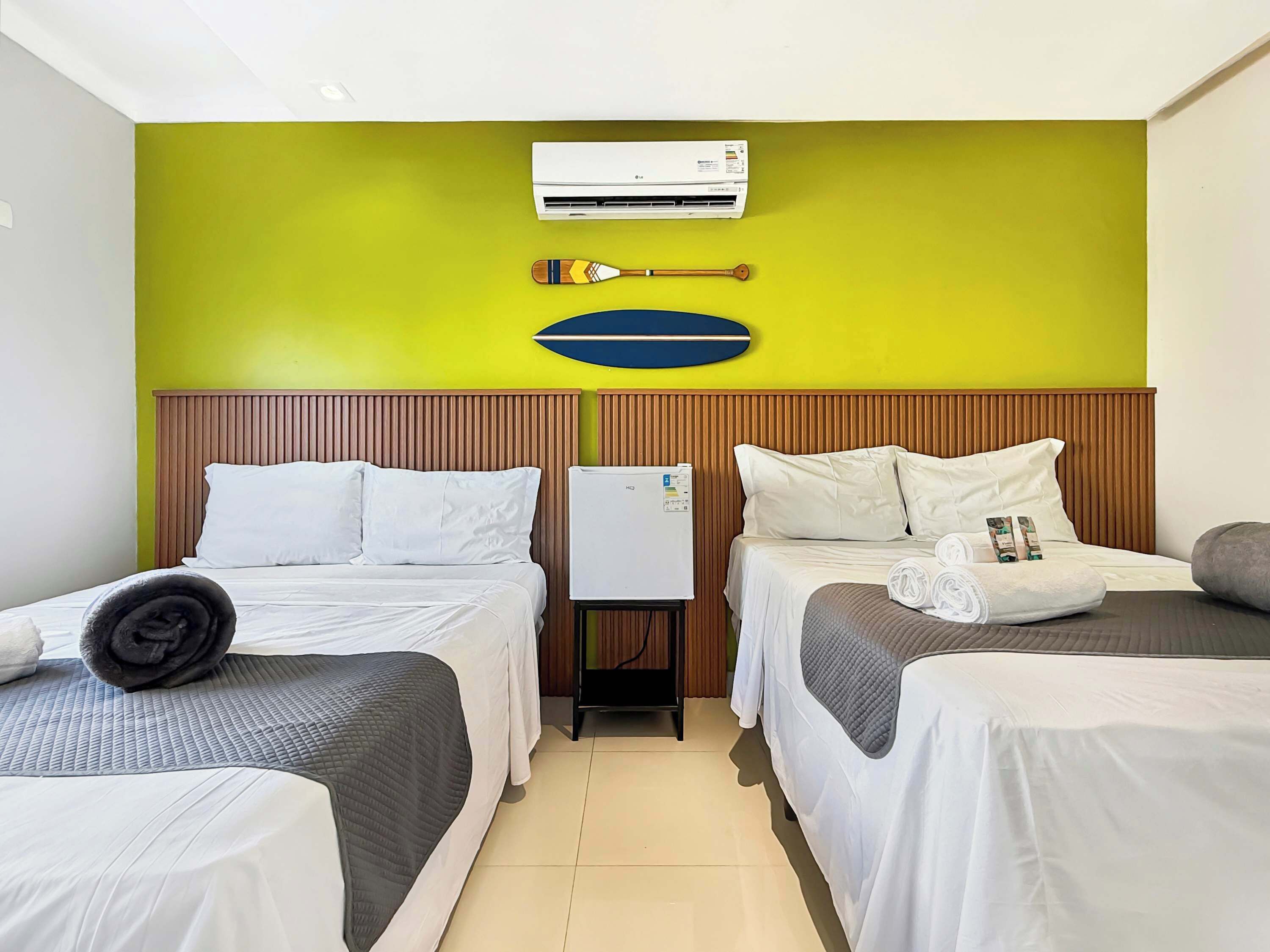 Ein Hotelzimmer mit zwei Betten, einer Wandklimaanlage und einem Holzkopfteil.