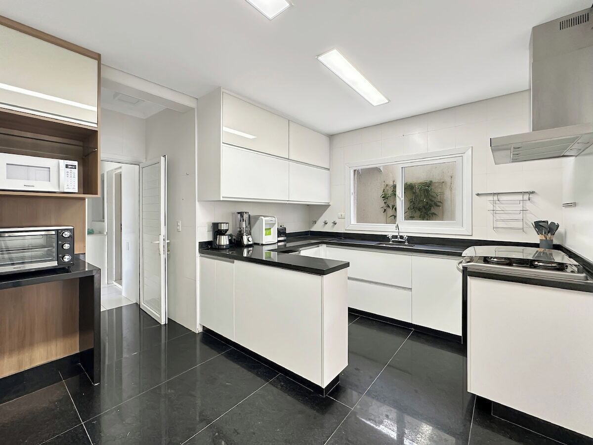 Una cocina moderna con armarios blancos, un microondas integrado, una cafetera y una estufa.