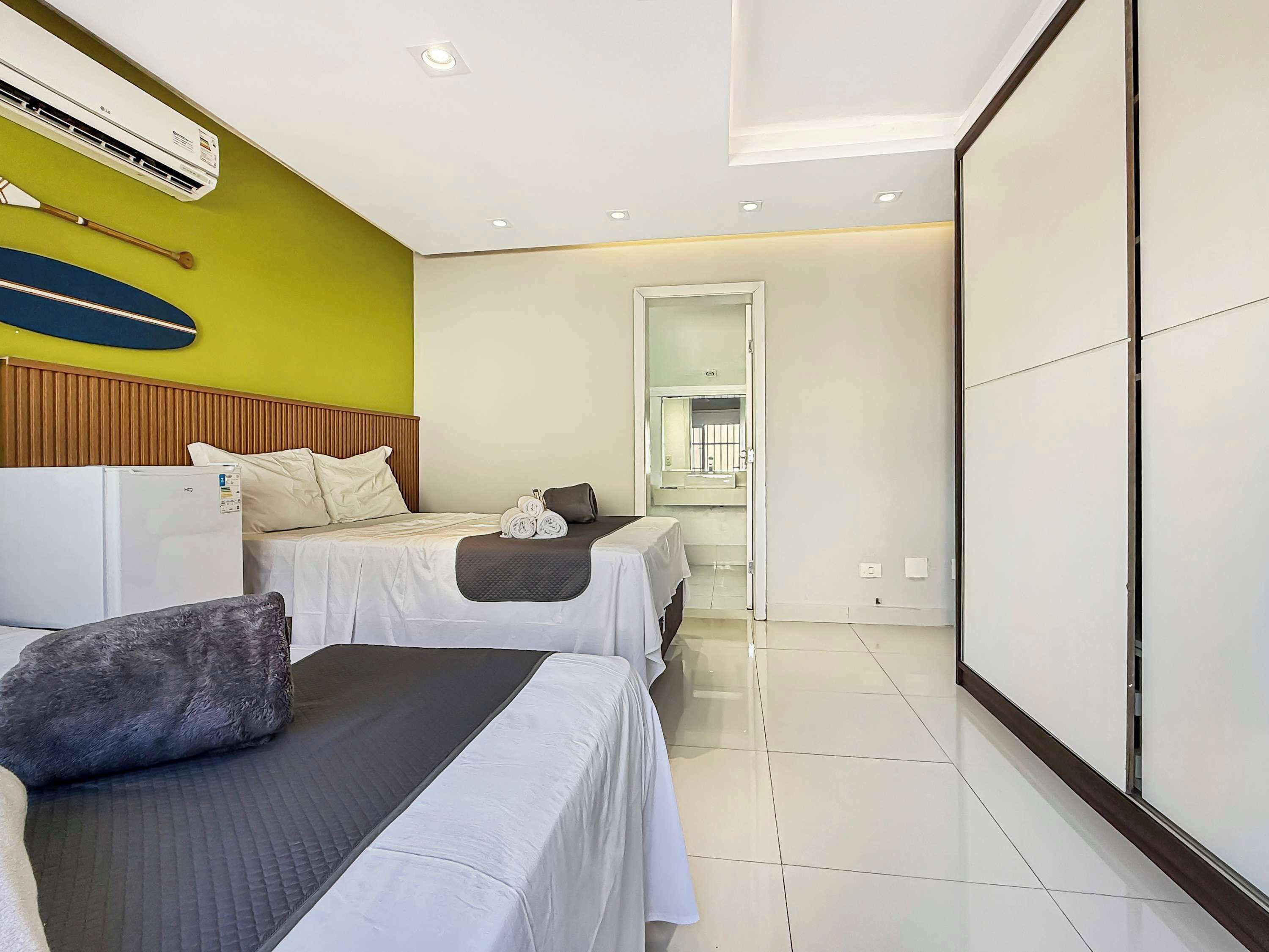 A hotel room with two beds, a wooden headboard, a large mirror, and a tiled floor.
