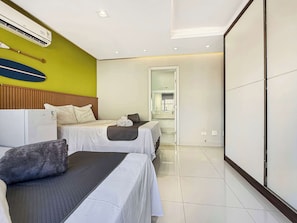 Une chambre d’hôtel avec deux lits, une tête de lit en bois, un grand miroir et un sol carrelé.