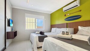 Quarto de hotel com duas camas, televisão, ar condicionado e janela com vista.