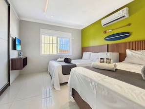 Una camera d'albergo con due letti, televisore, aria condizionata e una finestra vista.