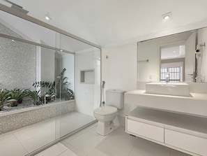 Un bagno moderno con box doccia in vetro, un water, un lavandino e un grande specchio.