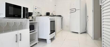 A modern kitchen with white cabinetry, a microwave, a coffee maker, and a refrigerator.