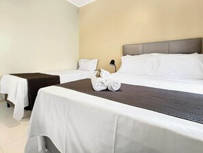 Una habitación de hotel con dos camas, una mesita de noche y una lámpara.