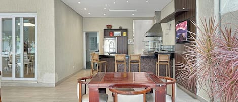 Una cucina moderna con zona pranzo, caratterizzata da un tavolo e sedie in legno, forno integrato e un'ampia finestra.