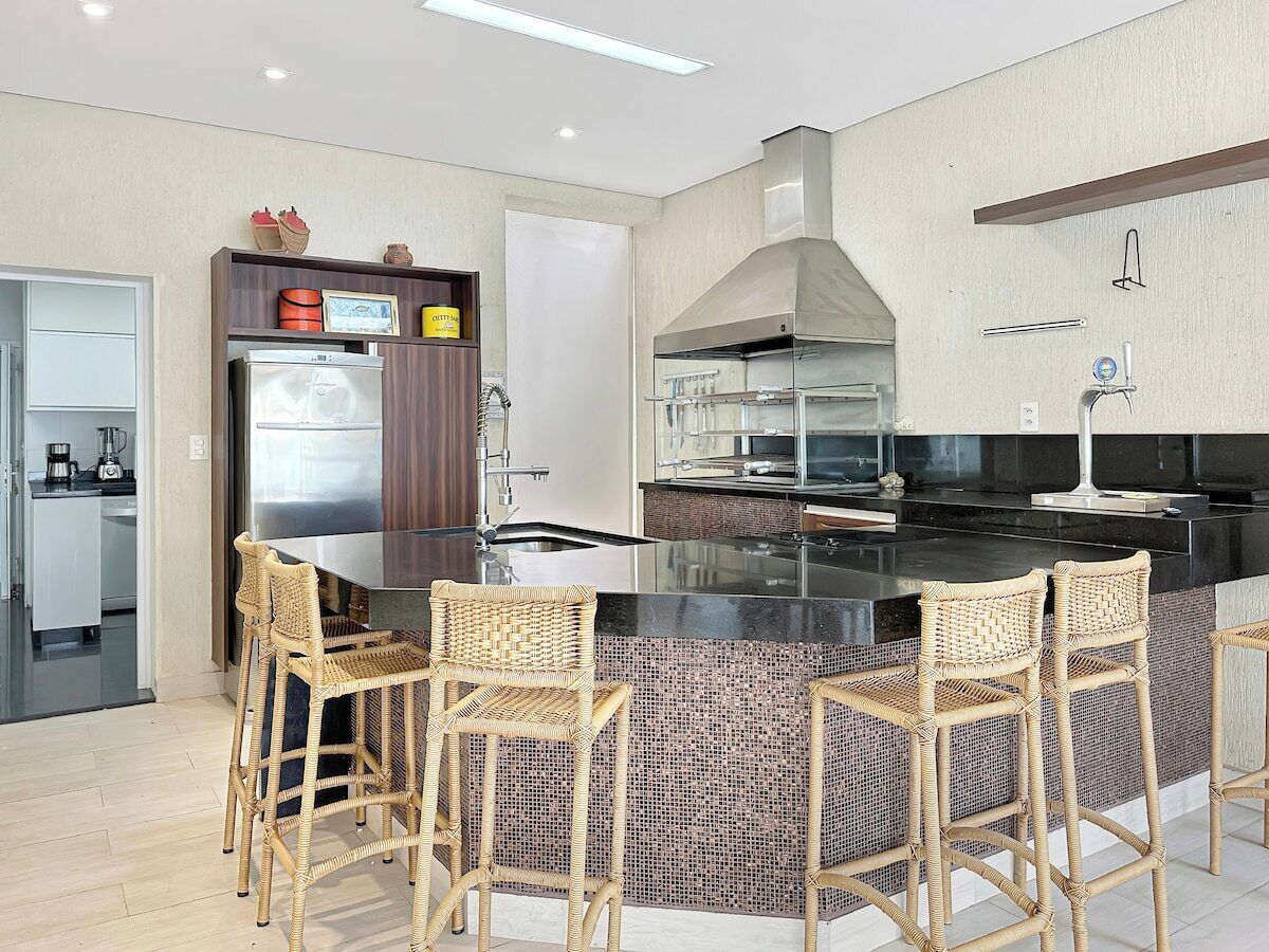 A modern kitchen with a central island, bar stools, and a built-in stove.