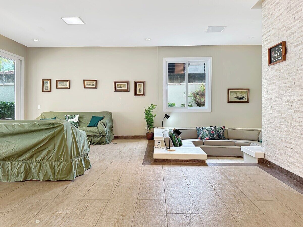 A spacious living room with a large window, a sofa set, a coffee table, and a wall-mounted picture frame.