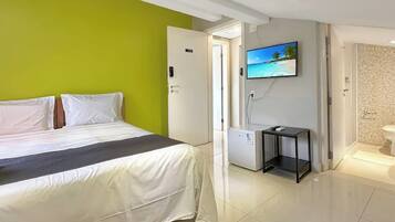 Ett hotellrum med en säng, en tv, ett litet bord och ett badrum som syns genom en öppen dörr.