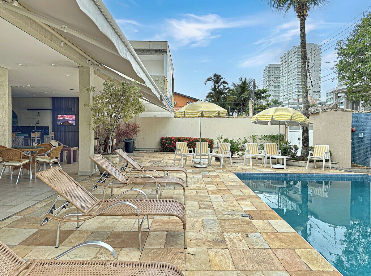 A poolside area with lounge chairs, a pool, and umbrellas.