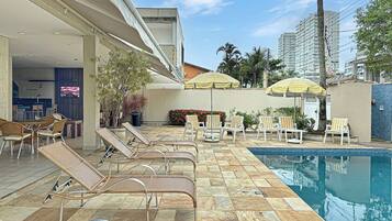 A poolside area with lounge chairs, a pool, and umbrellas.