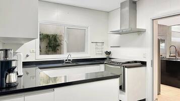 A modern kitchen with white cabinets, a black countertop, and stainless steel appliances.