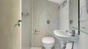 Un bagno con il water bianco, uno spazio doccia in vetro e un lavabo bianco con specchio.
