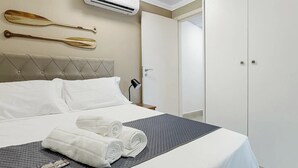 Quarto de hotel com cama, luminária, ar condicionado fixado na parede e guarda-roupa.