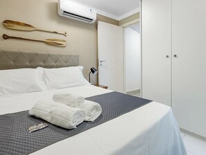 Una camera d'albergo con un letto, una lampada da comodino, un condizionatore d'aria a muro e un armadio.