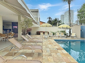 A poolside area with lounge chairs, a pool, and umbrellas.