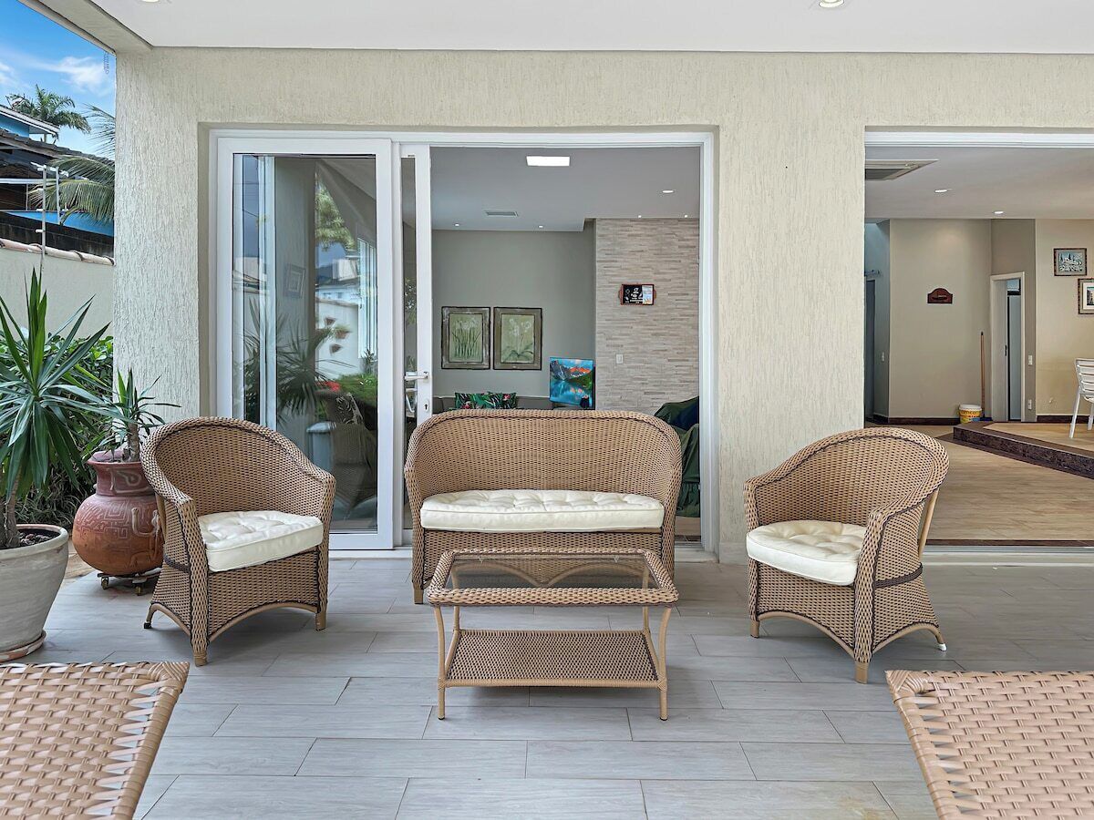A patio area with wicker furniture, including two chairs and a table, and a large potted plant.