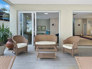 A patio area with wicker furniture, including two chairs and a table, and a large potted plant.