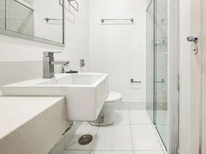 Un bagno moderno con lavandino bianco, water e cabina doccia in vetro.