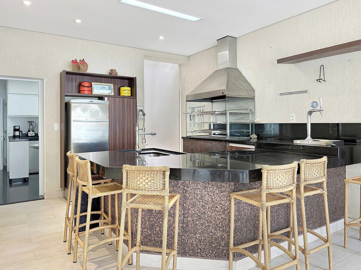 A modern kitchen with a central island, bar stools, and a built-in stove.