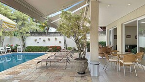 Uma área de piscina ao ar livre com espreguiçadeiras e uma mesa de jantar com cadeiras.