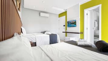 A hotel room with two beds, a television, an air conditioning unit, and a bathroom visible through an open door.