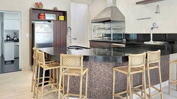A modern kitchen with a central island, bar stools, and a built-in stove.