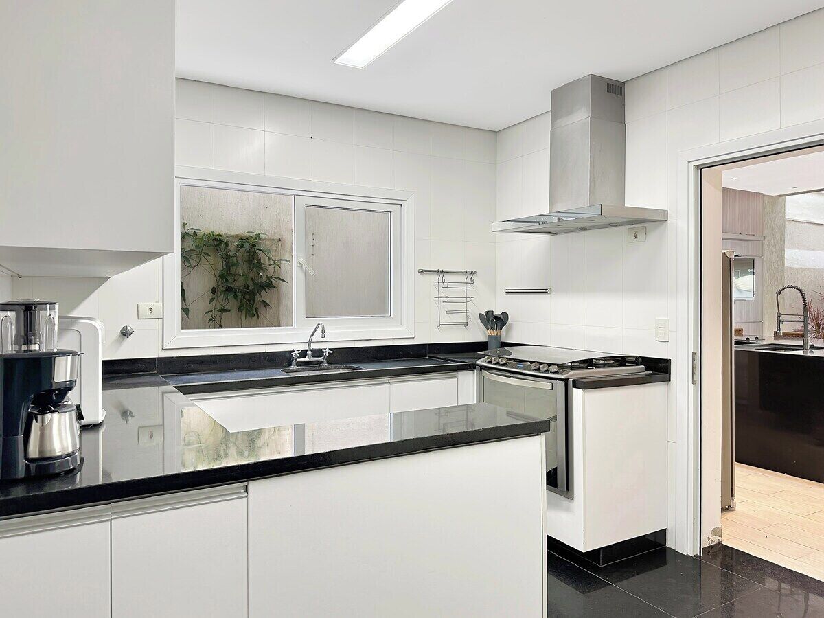 A modern kitchen with white cabinets, a black countertop, and stainless steel appliances.