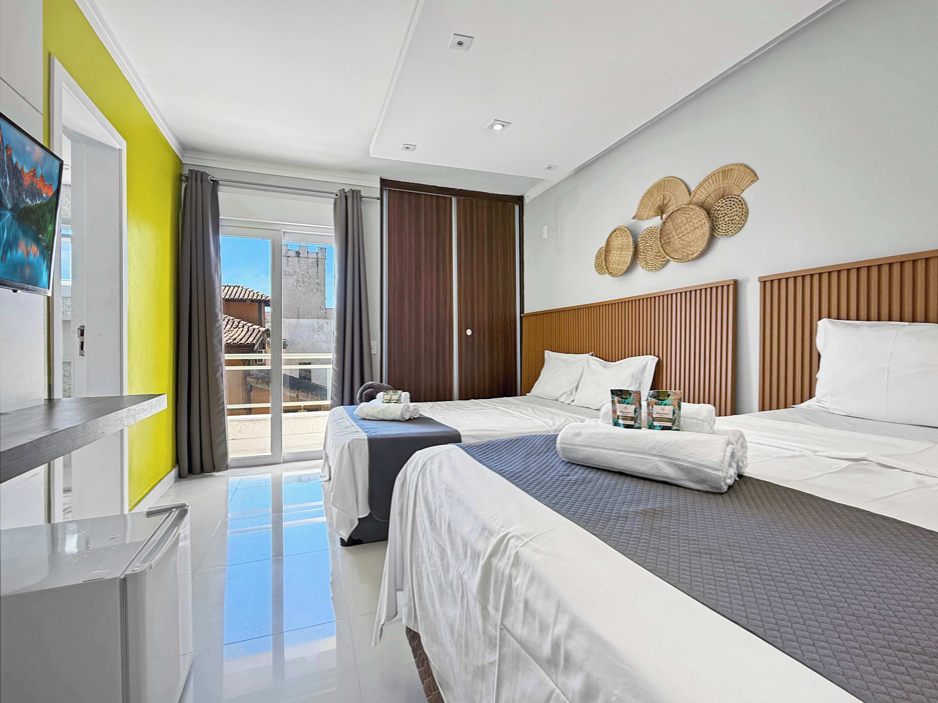 Ein Hotelzimmer mit zwei Betten, einer Schiebetür zum Balkon und einem an der Wand befestigten Dekorationsgegenstand.