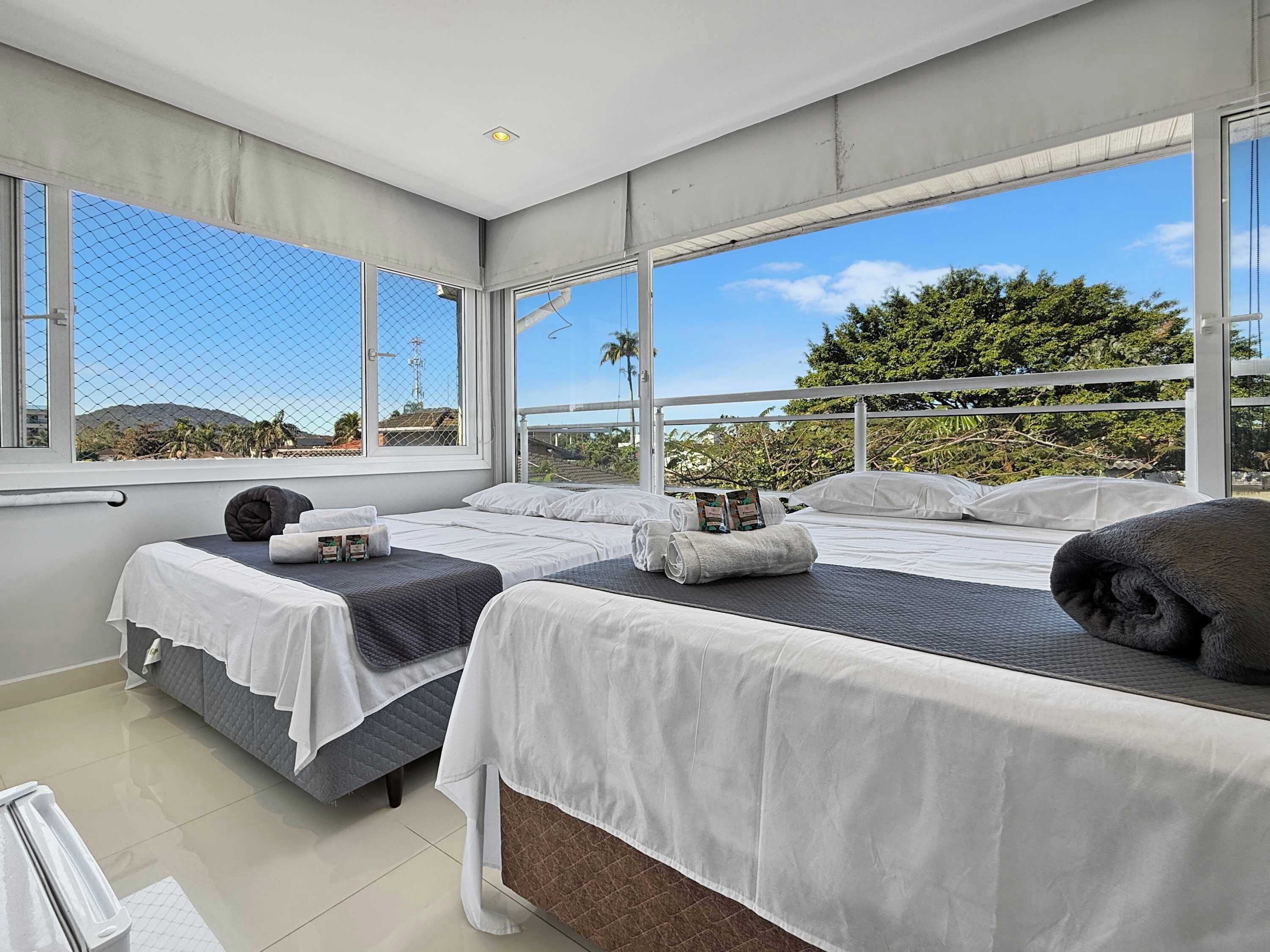 Habitación de hotel con dos camas, un ventanal grande y vistas al exterior.