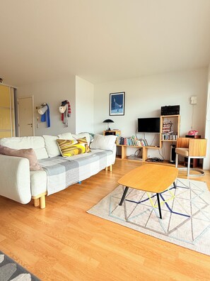 A living room with a sofa, a coffee table, a bookshelf, and a TV. - Lovely Apartment for 6 Guests (Knokke-Heist)