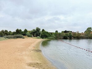 A sandy beach area adjacent to a calm body of water with a red floating barrier. - Lovely Apartment for 6 Guests (Knokke-Heist)