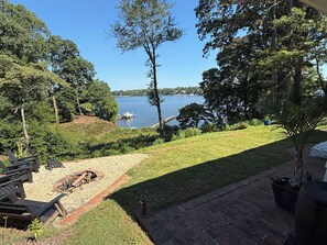 A patio area with a view of a lake, outdoor furniture, and a fire pit.