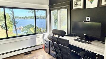Un bureau moderne doté d’une grande fenêtre donnant sur un plan d’eau, d’un bureau avec un ordinateur et d’une chaise.