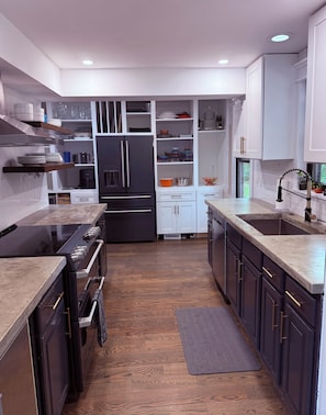 A modern kitchen with dark cabinetry, a central island, and built-in appliances.