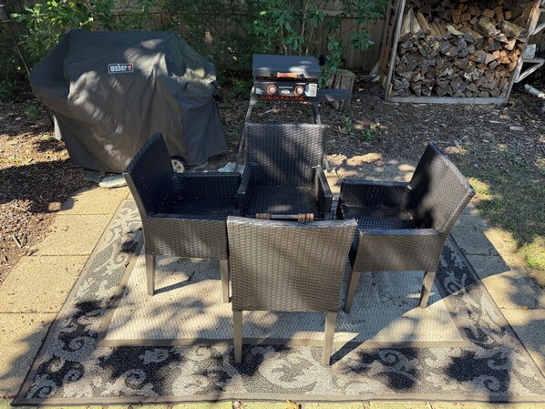 Zona exterior amb mobiliari per seure, una barbacoa i taula coberta.