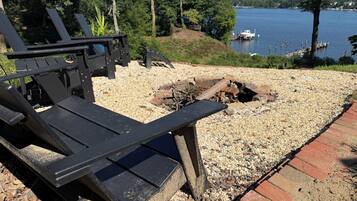 Une terrasse au bord du lac, avec des fauteuils Adirondack, un foyer et une vue sur le lac.