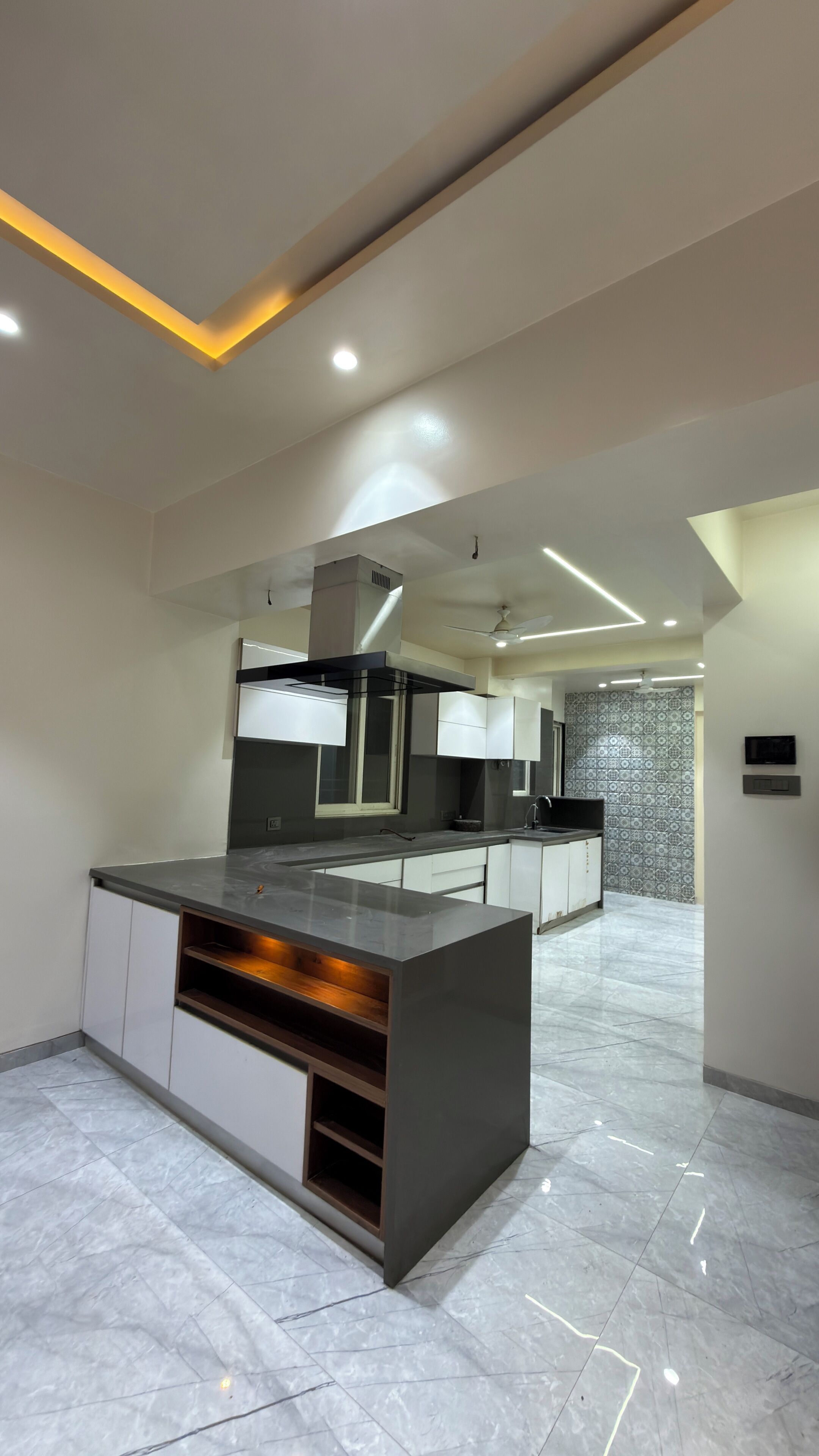 Et moderne køkken med en central ø, integreret hårde hvidevarer og et mønstret backsplash.
