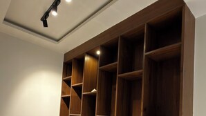 A room with a large wooden shelving unit against the wall, a ceiling light fixture, and a tiled floor. - 3BHK Pavillion Penthouse Near Viman Nagar by Velvet Stays (Pune)