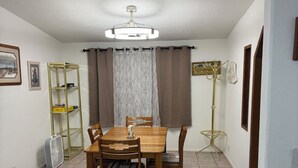 A dining area with a wooden table and chairs, a ceiling fan, and a floor lamp.