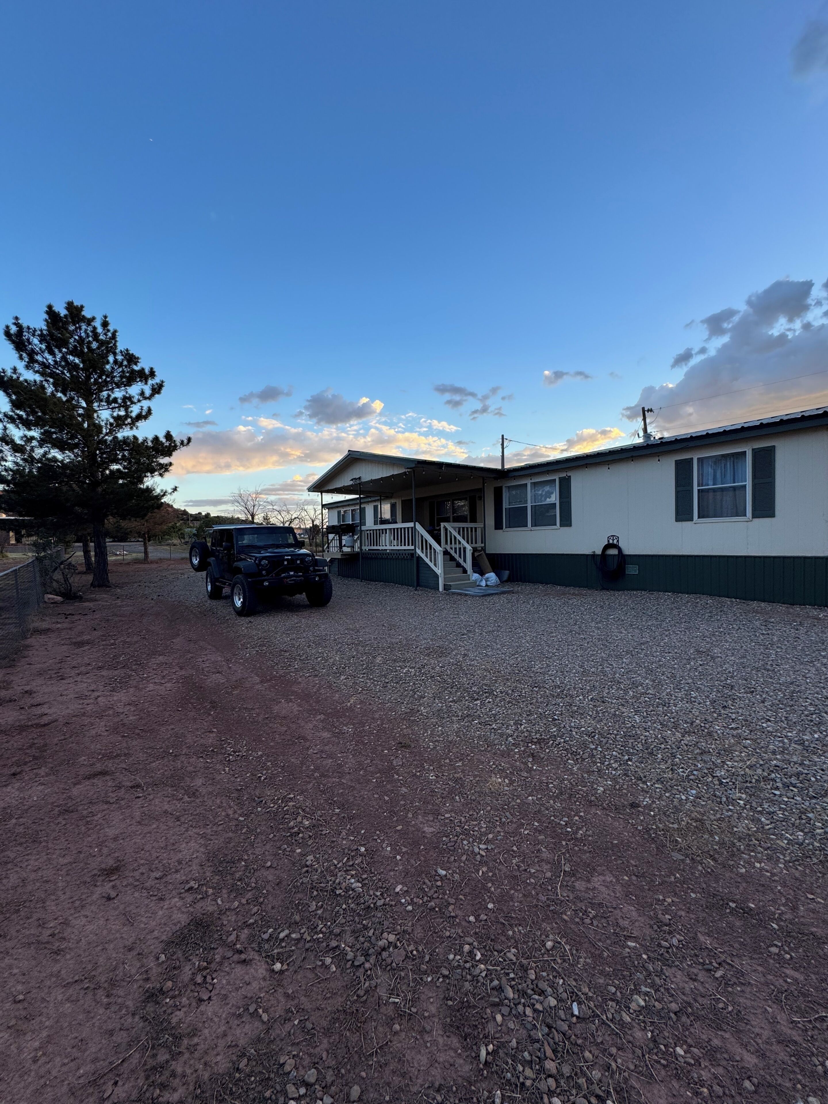 A building with a gravel driveway, a parked vehicle, and a tree.
