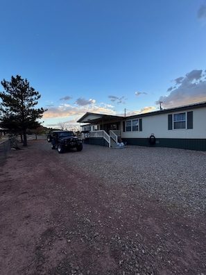 A building with a gravel driveway, a parked vehicle, and a tree.
