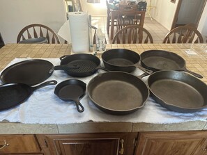 A kitchen counter with various cookware items including frying pans, a griddle, and a small pan.