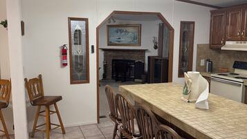 A dining area with a long table, wooden chairs, a ceiling fan, and a fireplace.