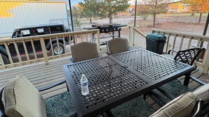 En uteplats med ett bord och stolar, en grill och ett fordon i bakgrunden.