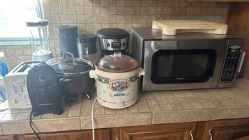 A kitchen with a microwave, toaster, slow cooker, and a coffee maker.