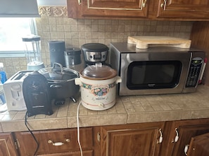 A kitchen with a microwave, toaster, slow cooker, and a coffee maker.